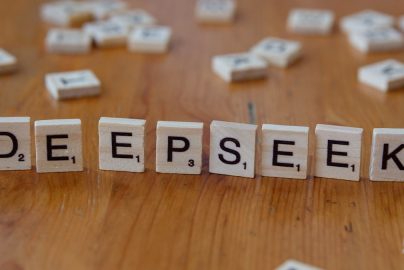 A wooden table topped with scrabble tiles spelling the word depeseek